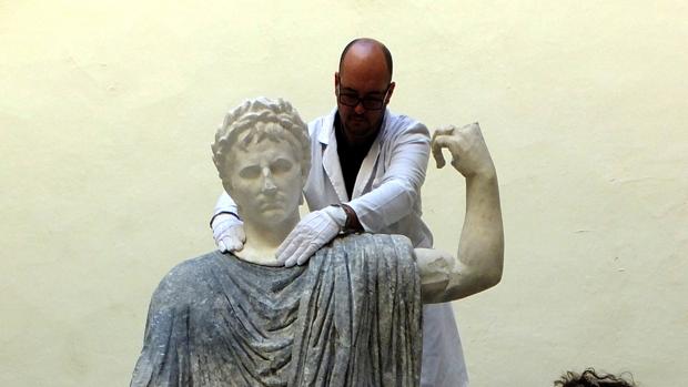 Un técnico coloca la cabeza a una escultura de Torreparedones